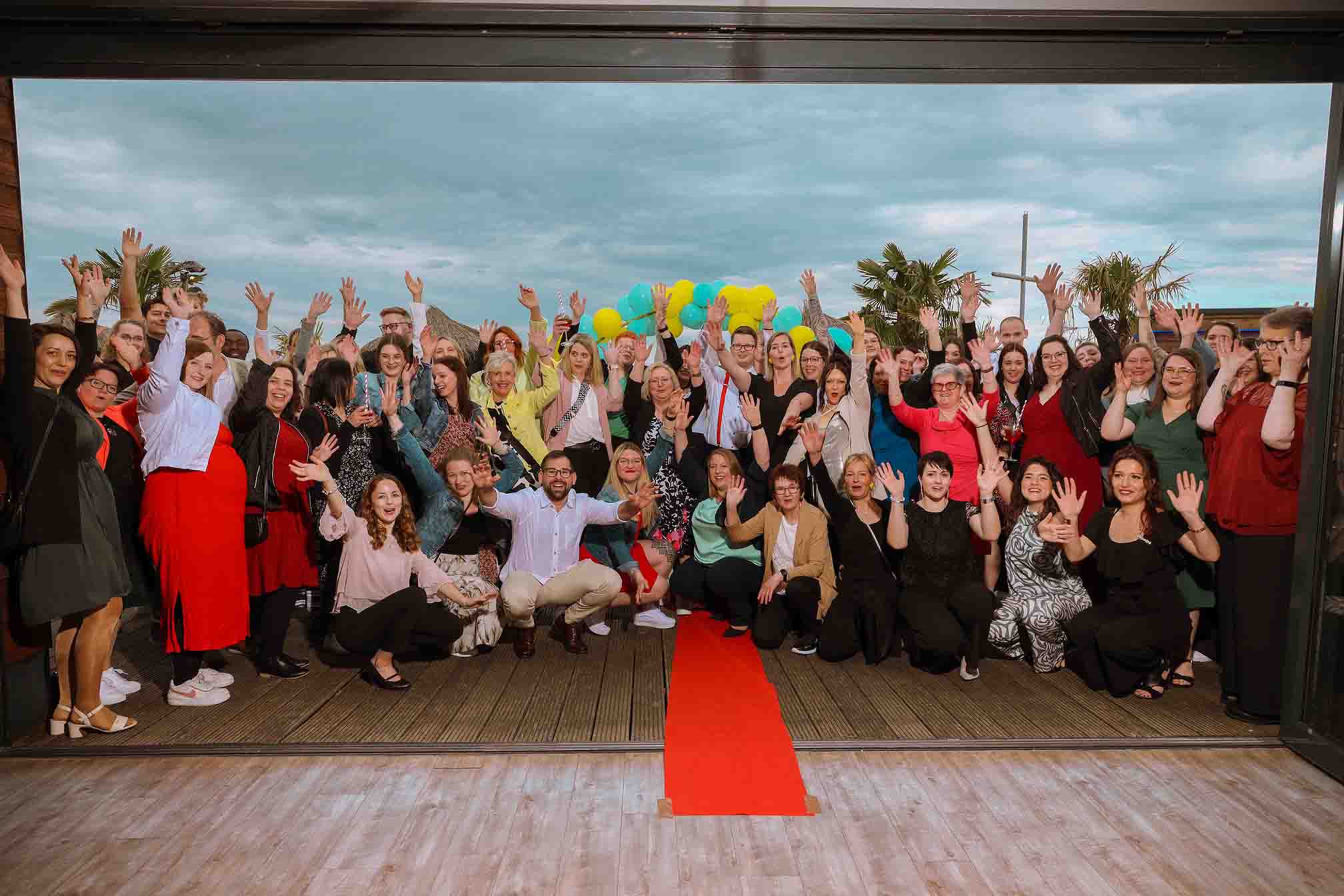 Großes Team von Miteinander feiert das 5-jährige Jubiläum mit einem Gruppenfoto am roten Teppich
